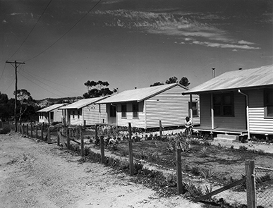 Black and white photo of four woddern huts
